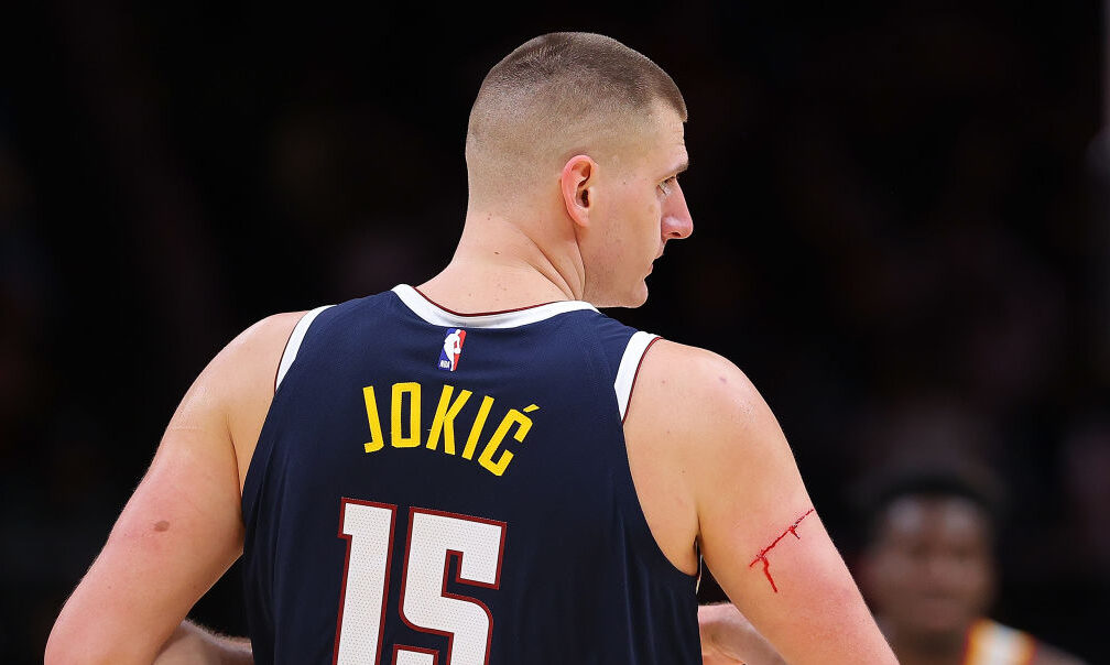 Nikola Jokic #15 of the Denver Nuggets reacts as an official calls a timeout to have the cut on his...