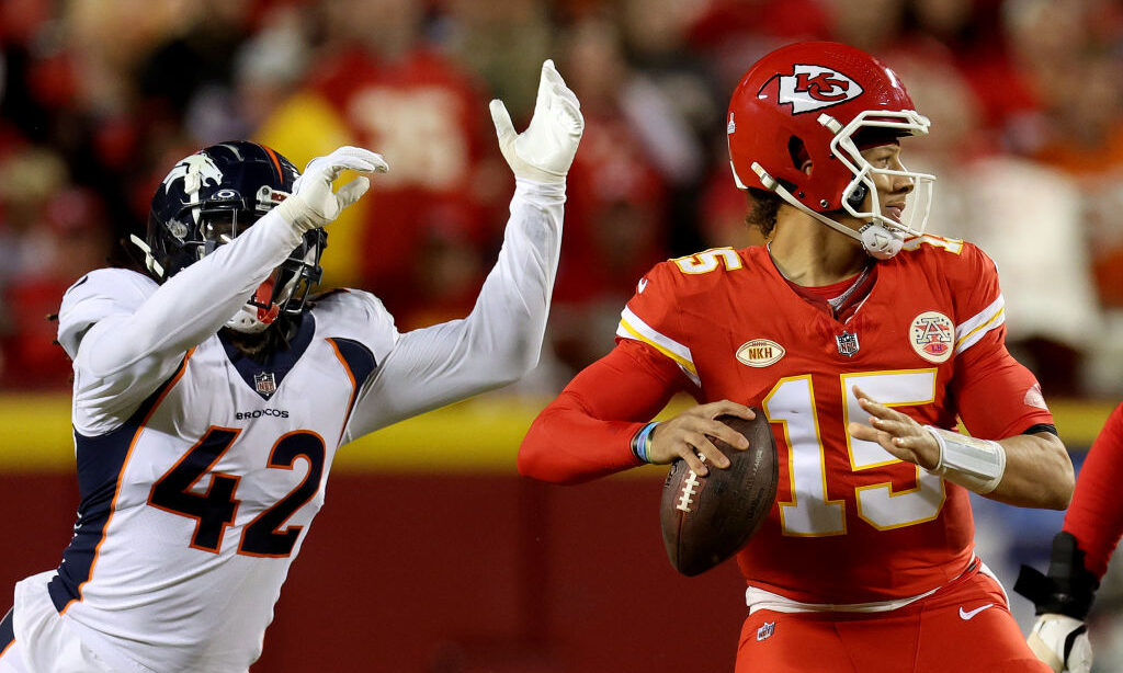 Patrick Mahomes #15 of the Kansas City Chiefs looks to pass while pressured by Nik Bonitto #42 of t...