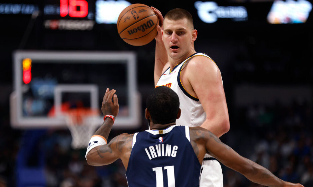 Nikola Jokic #15 of the Denver Nuggets handles the ball as Kyrie Irving #11 of the Dallas Mavericks...