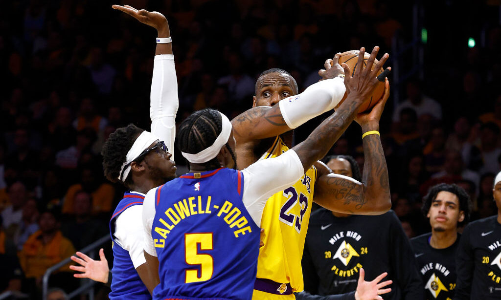 LeBron James #23 of the Los Angeles Lakers is defended by Reggie Jackson #7 and Kentavious Caldwell...