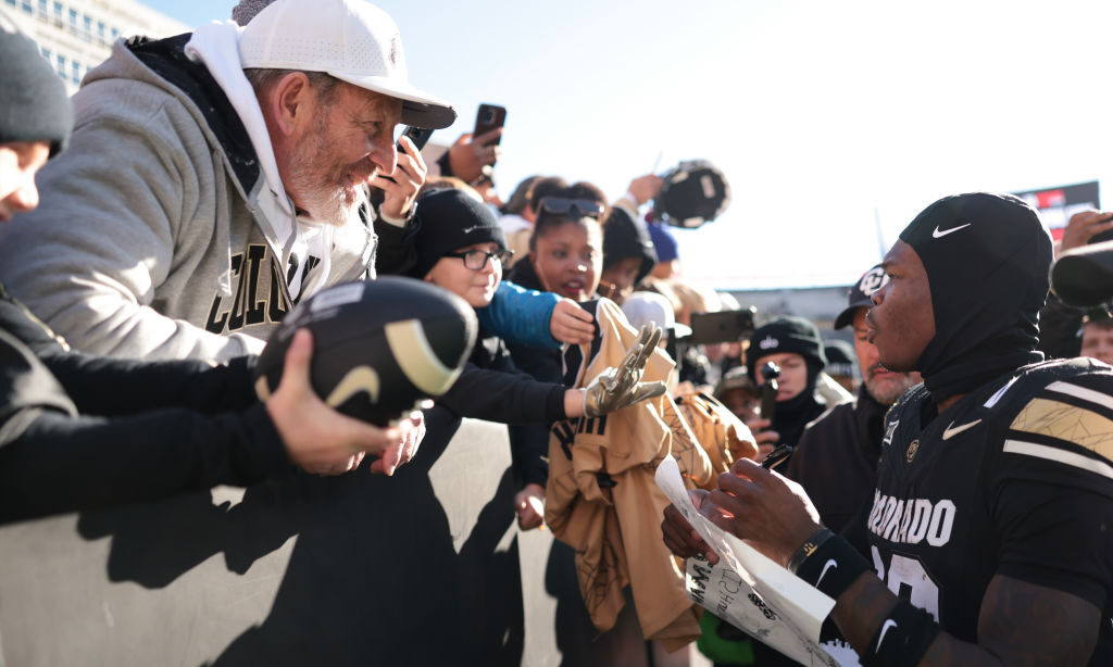 Travis Hunter #12 of the Colorado Buffaloes signs autographs for fans after the game against the Ok...