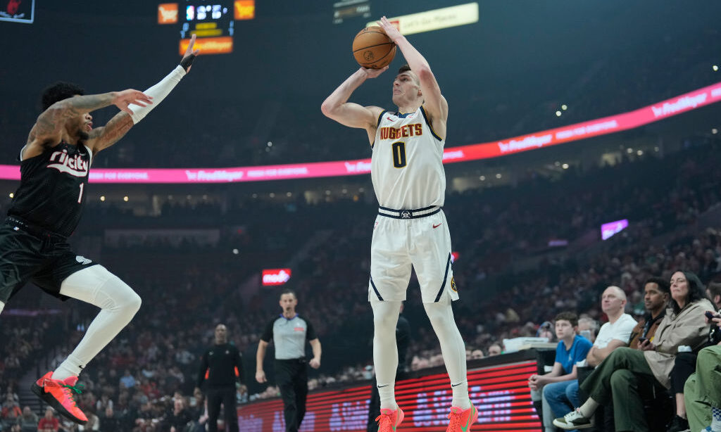 Christian Braun #0 of the Denver Nuggets shoots the ball against Anfernee Simons #1 of the Portland...